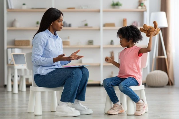 Child about to throw a teddy bear at adult