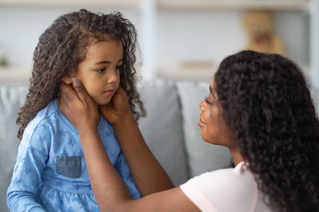 Adult holding upset child's face to comfort her